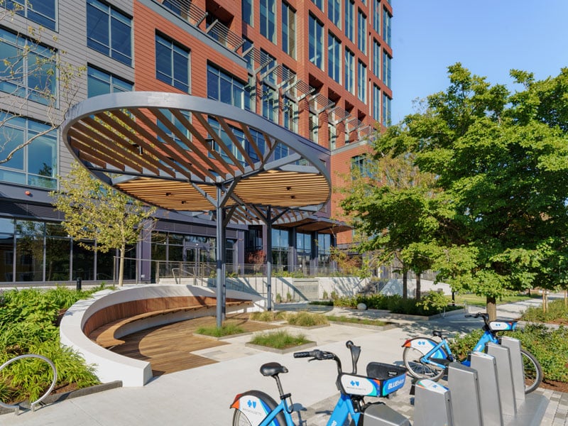 Modern building plaza featuring bike rentals and curved seating at 40 Thorndike in Cambridge