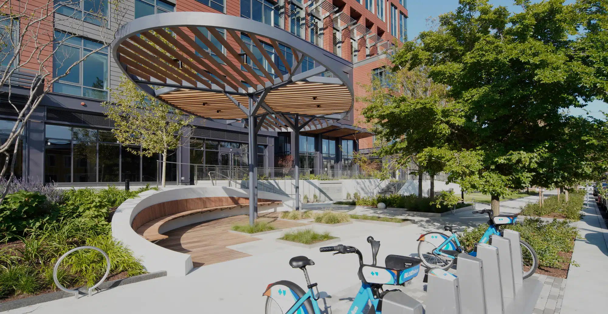 Modern office building with unique sustainable design, featuring a shaded outdoor plaza and bike share station